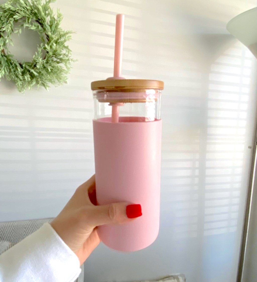 hand holding a pink silicone and glass tumbler with straw