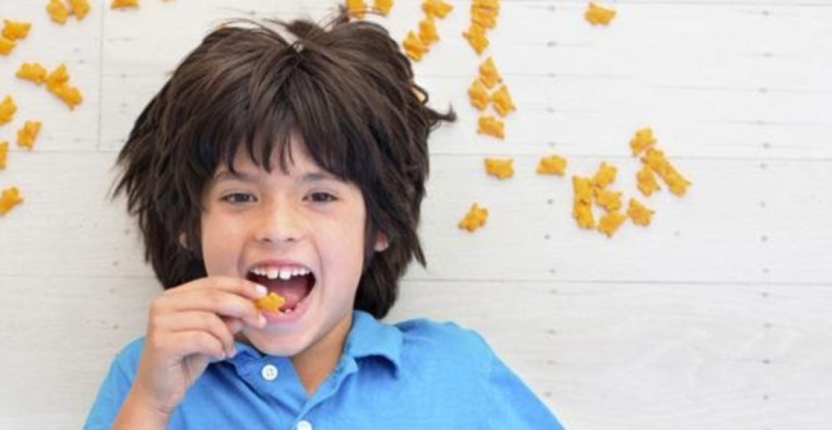 kid eating crackers wtih crackers laying around him