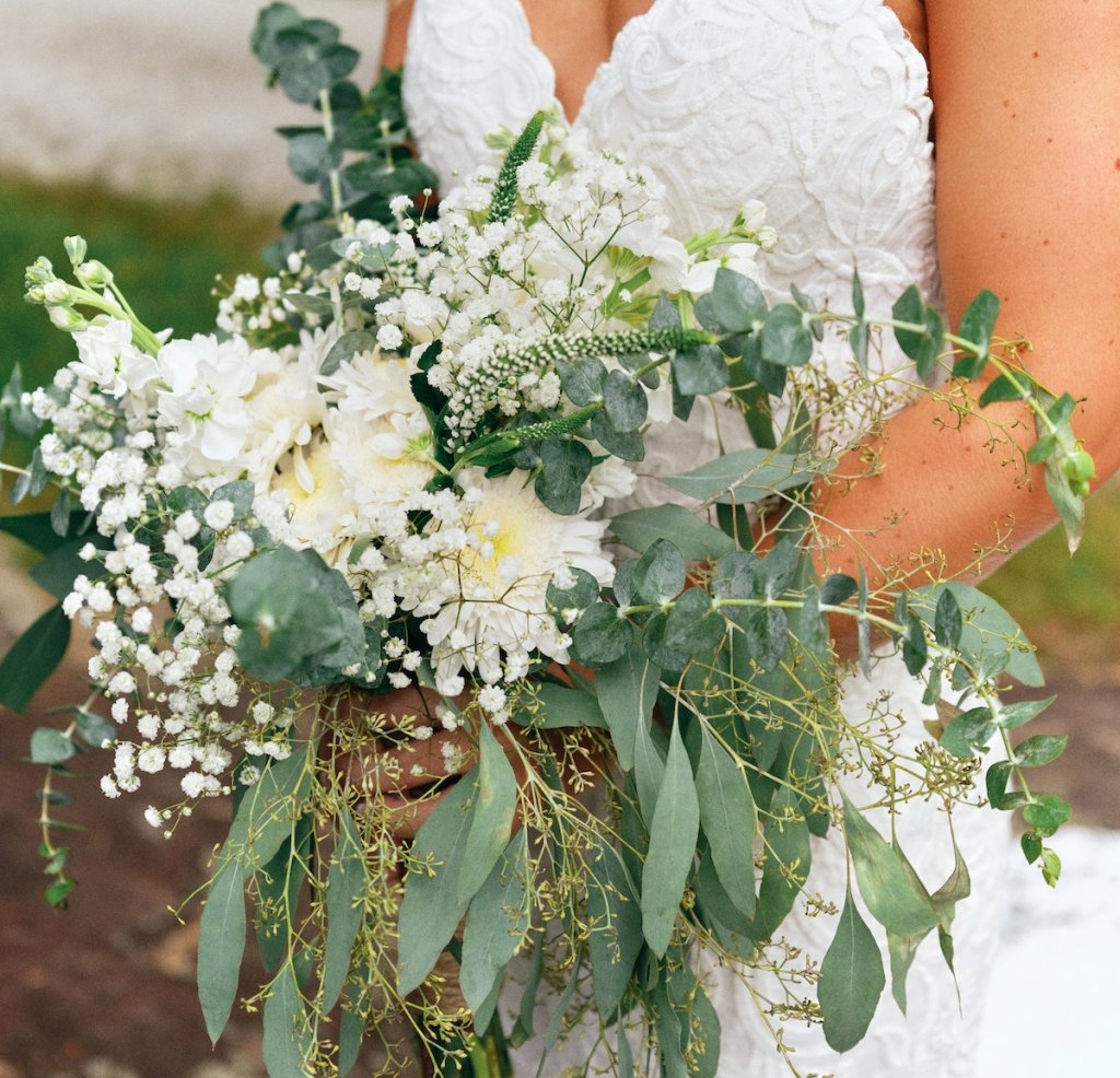 bride holding green and white bouquet wedding ideas on a budget
