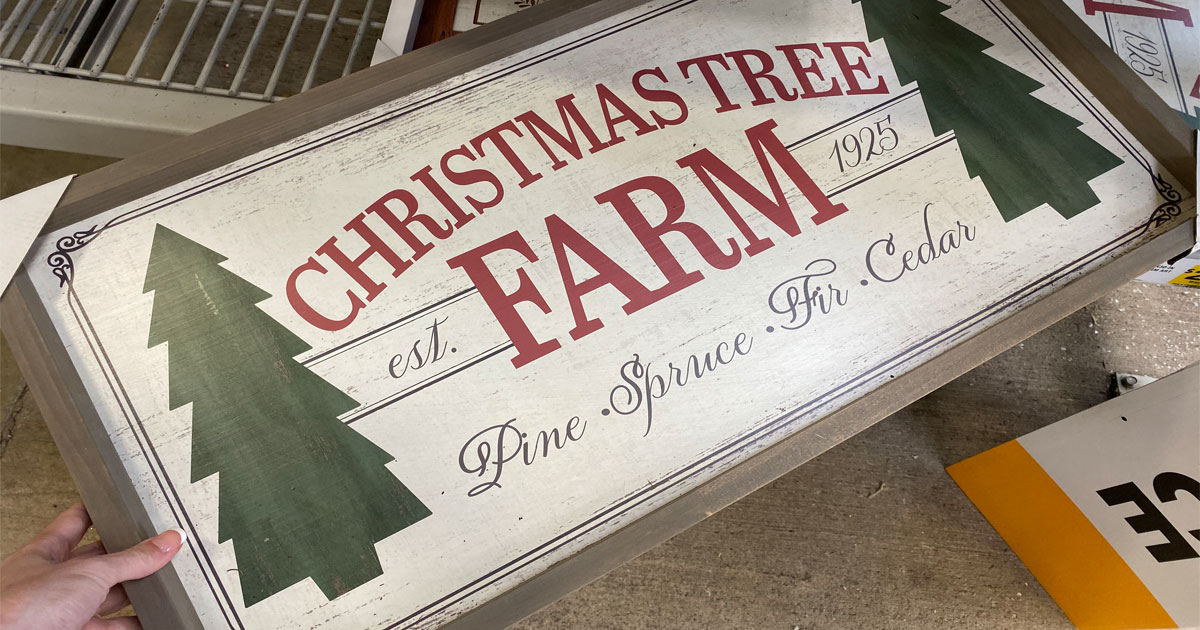 woman holding a christmas tree farm sign