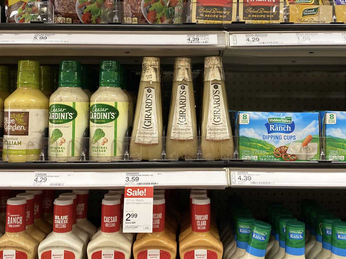 bottles of salad dressing on a shelf in a store with sale tags