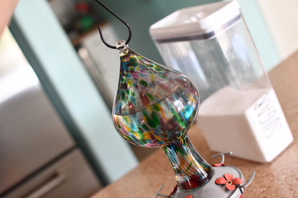 hummingbird feeder with hummingbird food recipe on counter