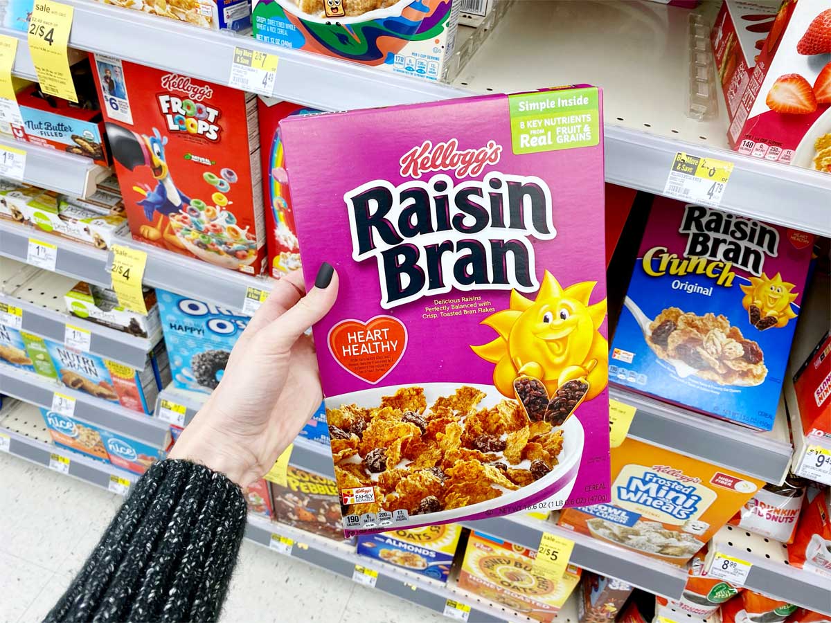 hand holding a brand name box of cereal in a store