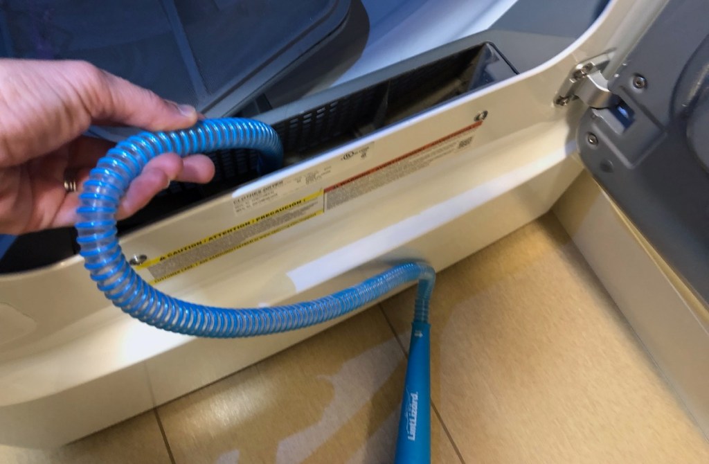 hand holding blue hose in dryer vent opening