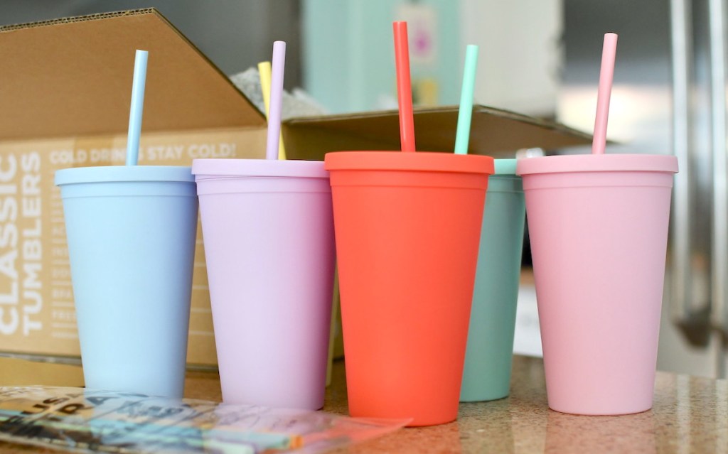 row of pastel-colored tumblers with straws sitting on countertop