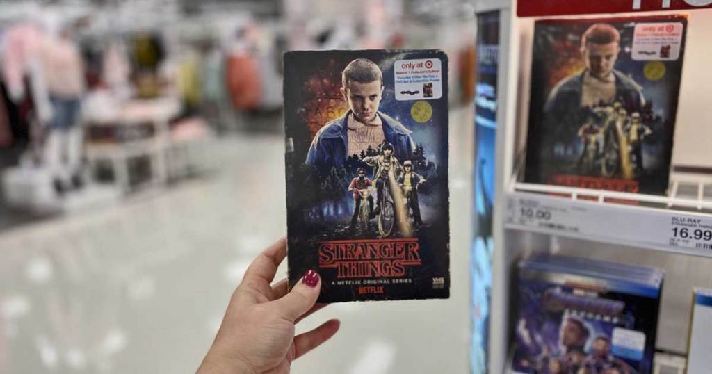 woman holding Stranger Things Seasons 1 & 2 DVD + Blu-ray, 4K UHD up in a store by the display