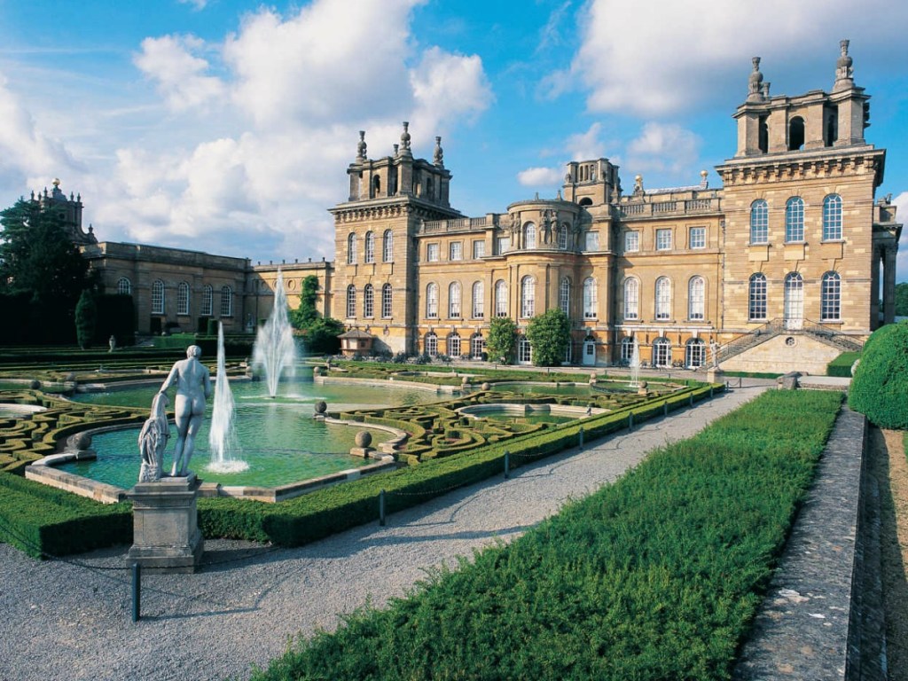 castle with water in front and statues with greenery
