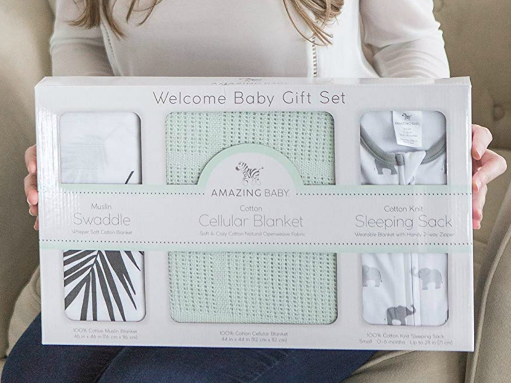 Woman holding a baby gift set with three blankets in packaging