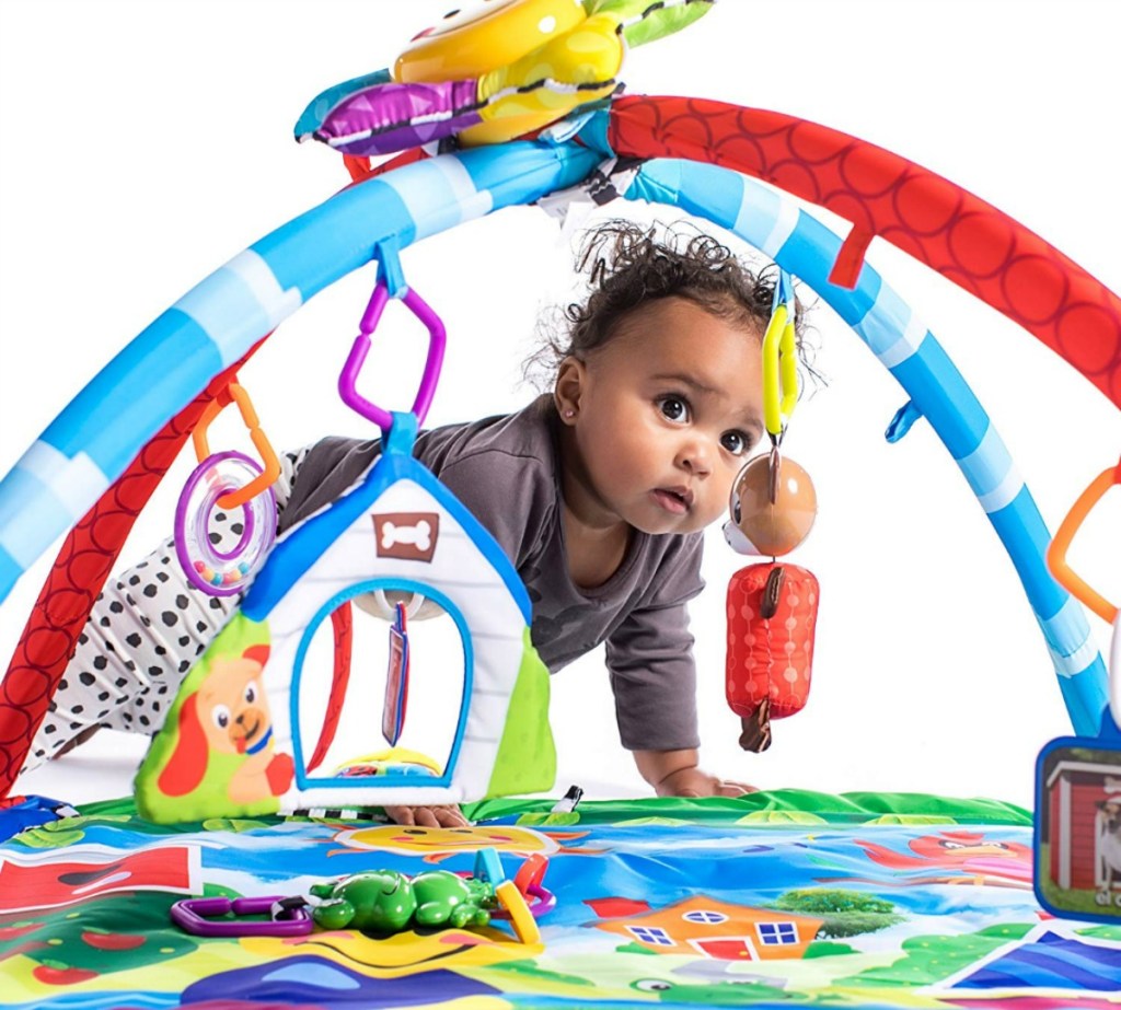 baby crawling through a colorful play gym
