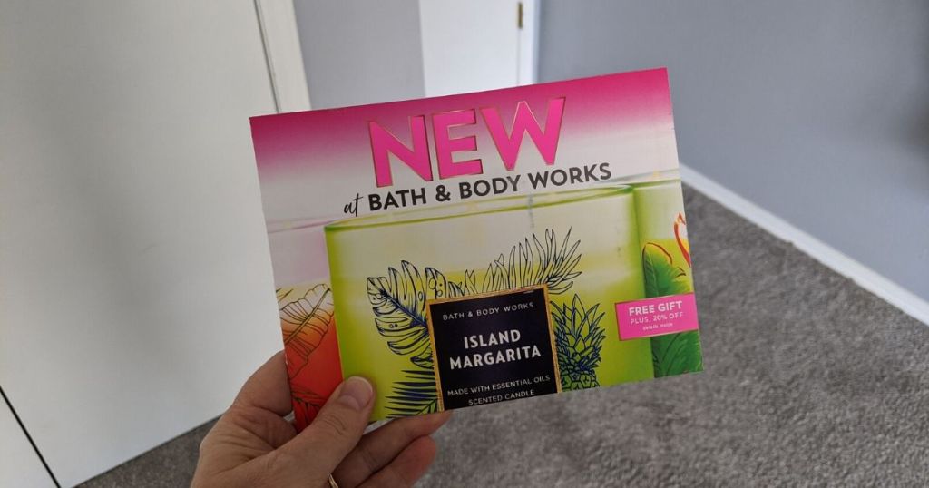 woman's hand holding bath body works mailer with coupons inside