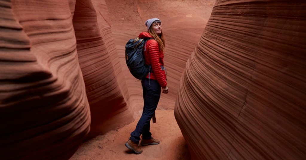 woman walking through a canyon wearing a backpack