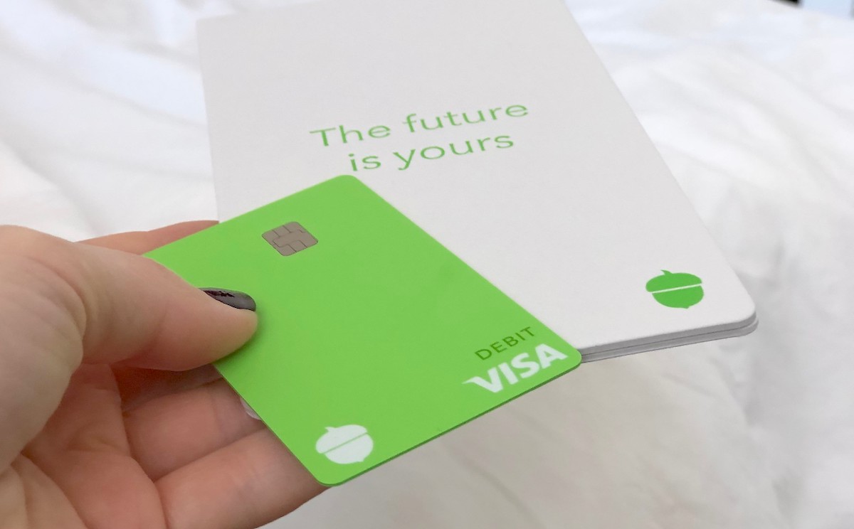hand holding a green visa card with white pamphlet