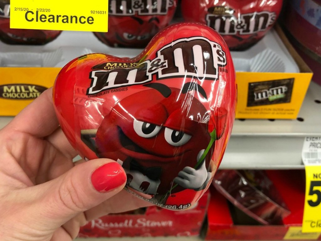 Woman's hand holding a plastic heart filled with M7Ms chocolate candies