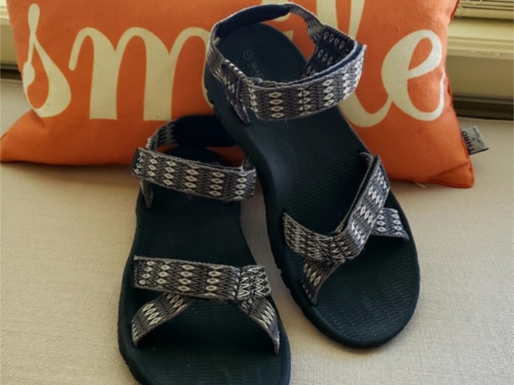 Black women's sandals against orange "Smile" pillow