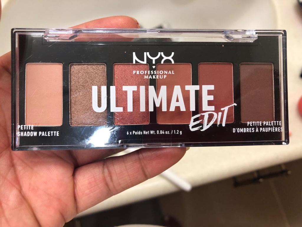 holding NYX eyeshadow palette 