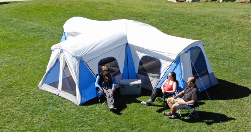 people sitting outside large tent on grass