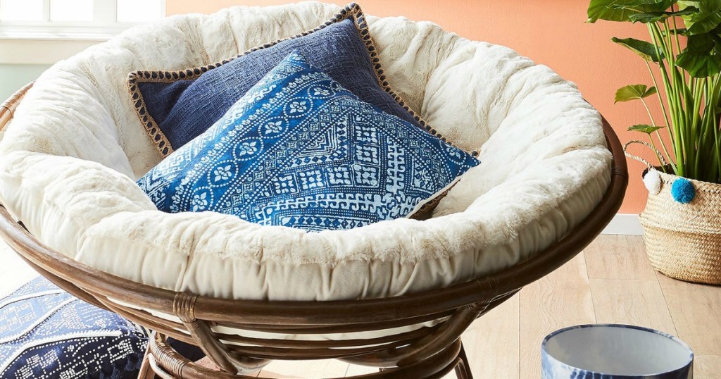 Papasan chair with white cushion and pillows on it