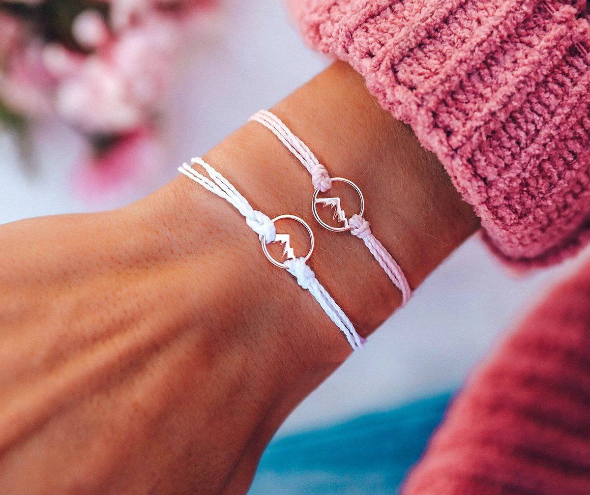 woman in pink sweater wearing two Pura Vida Rose Gold Sierra Charm Bracelets