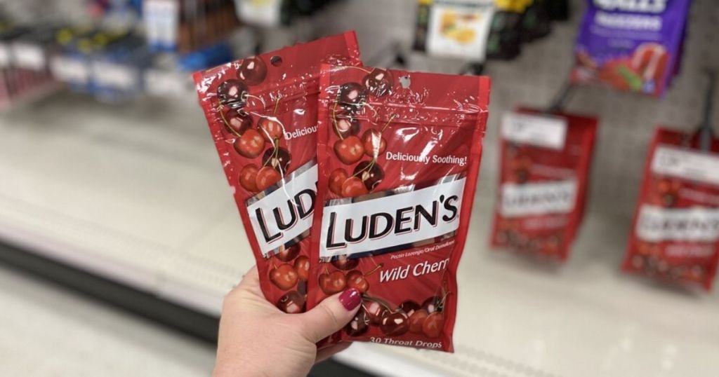 woman's hand holding two bags of cough drops