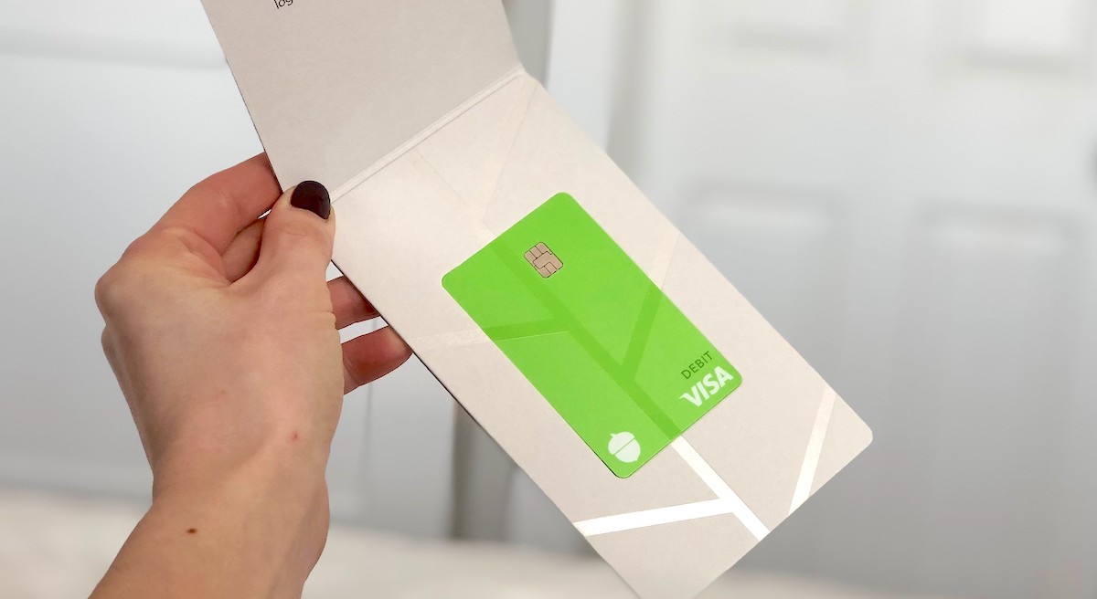 hand holding a green visa card in white pamphlet