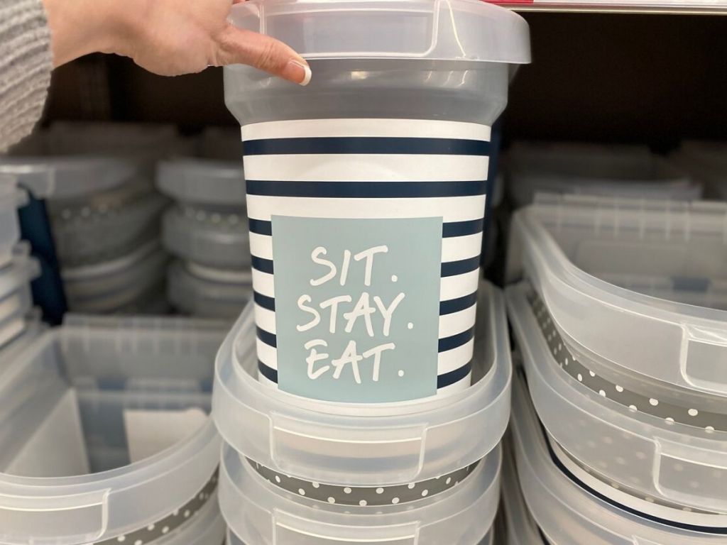 woman's hand pulling plastic ped food storage container out of stack of brand new ones on shelf at store