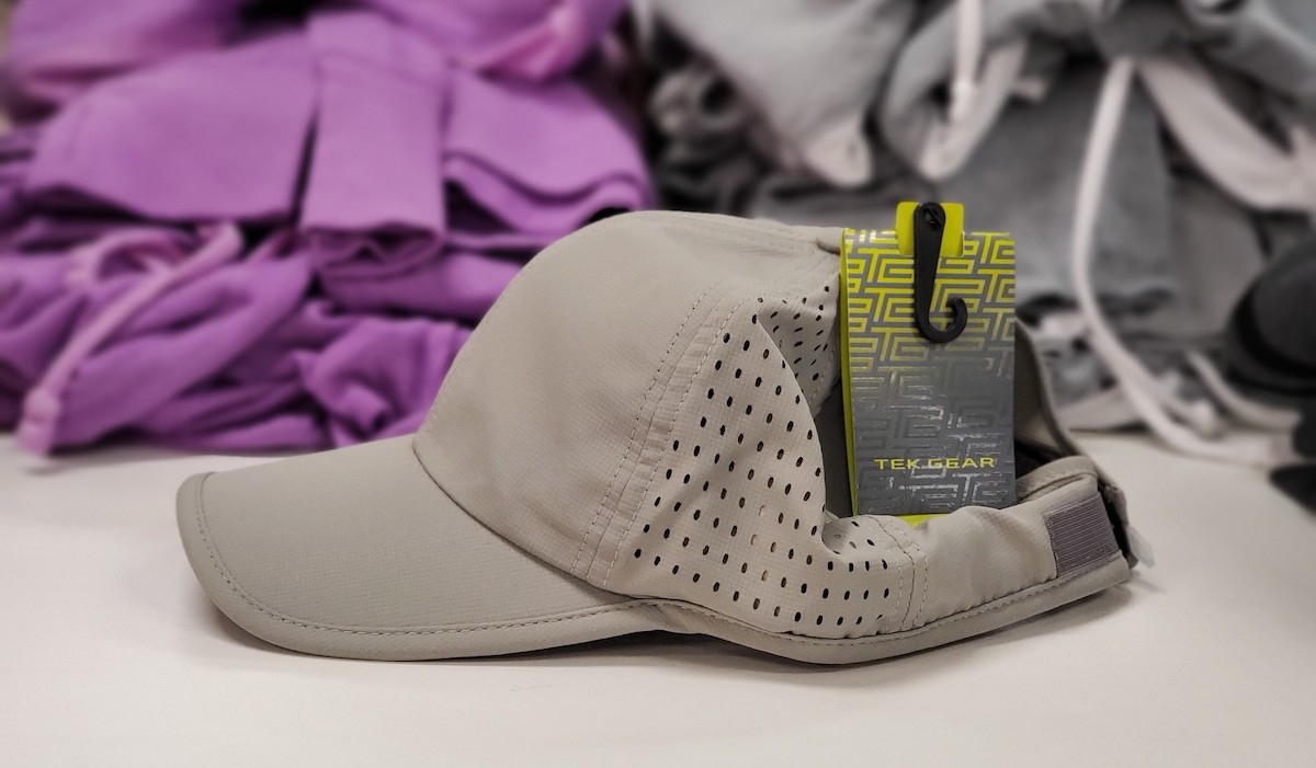 gray baseball hat sitting on store counter with clothes in the background