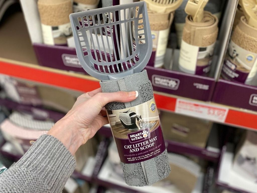 woman's hand holding a cat litter scooper with catch mat wrapped around handle in packaging 