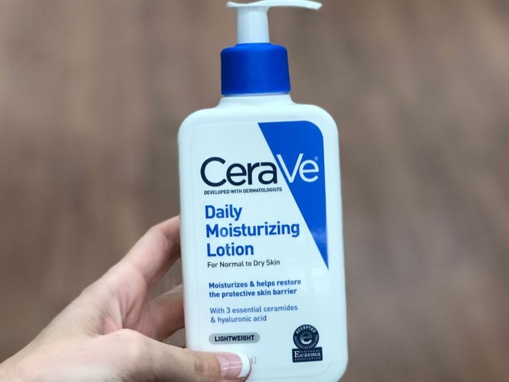 woman's hand holding bottle of lotion