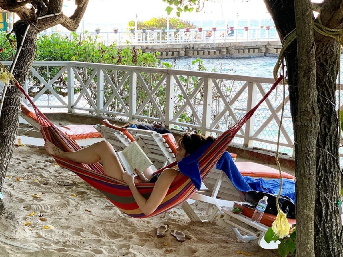 woman reading book in hammock on beach