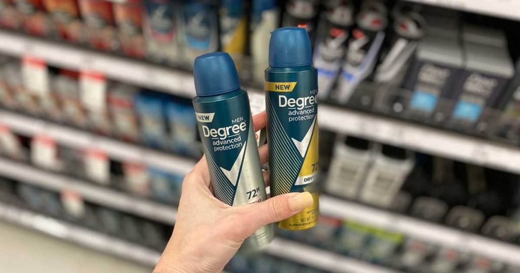hand holding two cans of deodorant spray in a store