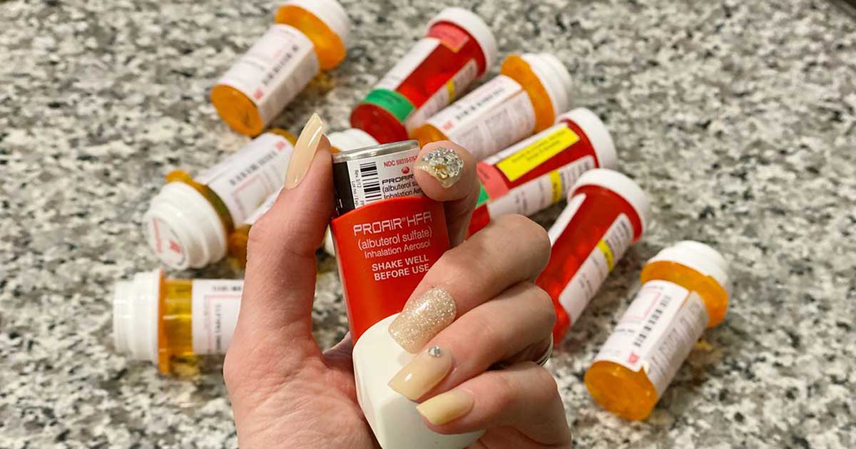 hand holding medicine in front of other prescription bottles