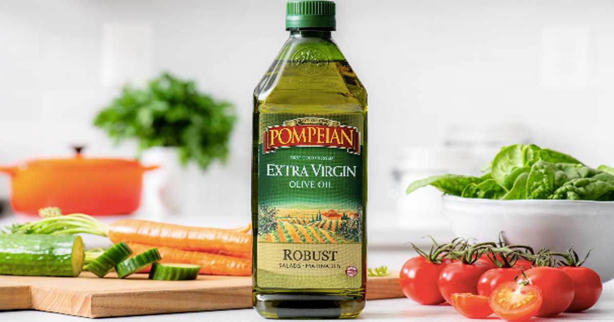 large bottle of extra virgin olive oil on table with food 