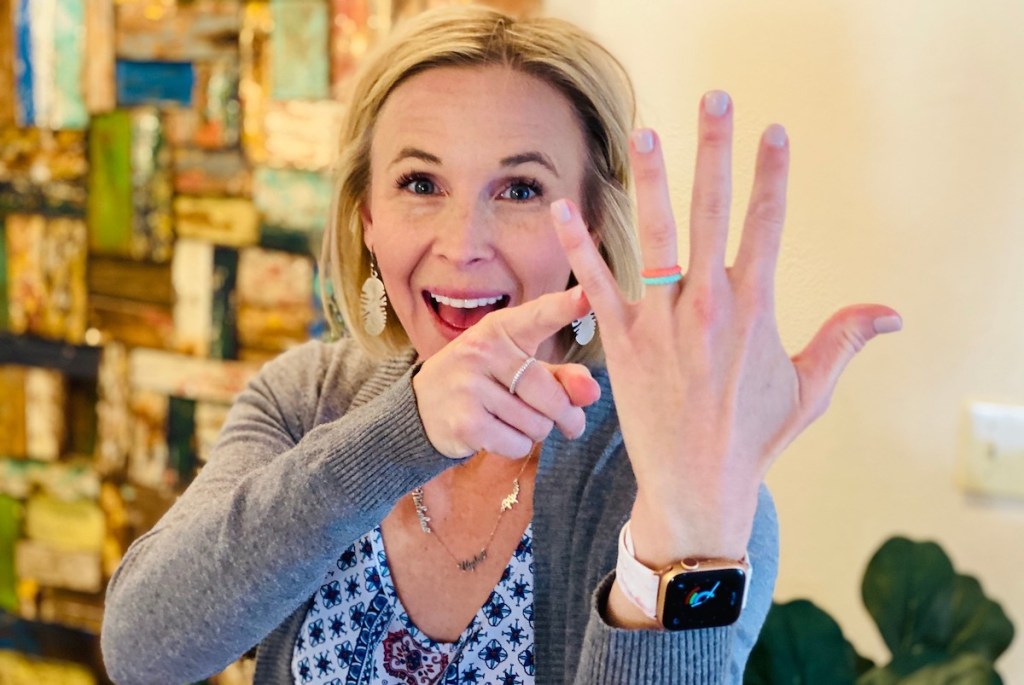 Woman smiling pointing to her ring finger with silicone alternative engagement rings