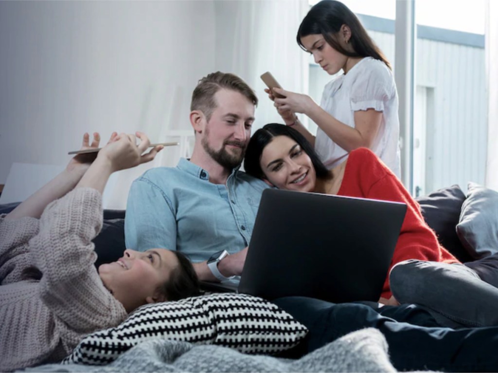 family together on couch using electronics