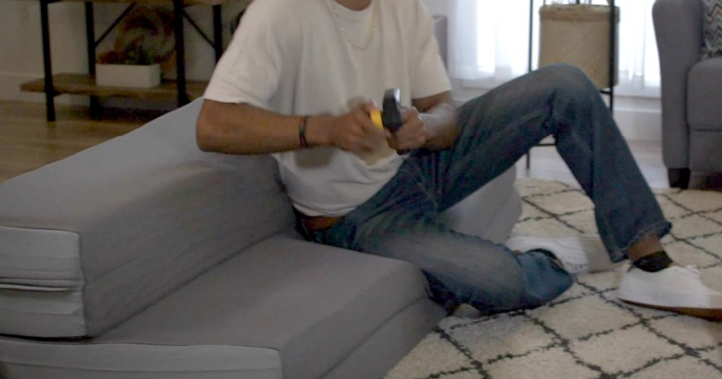 man sitting on mattress playing video game