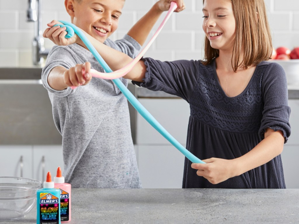boy and girl stretching slime with elmers blue and pink glue on counter