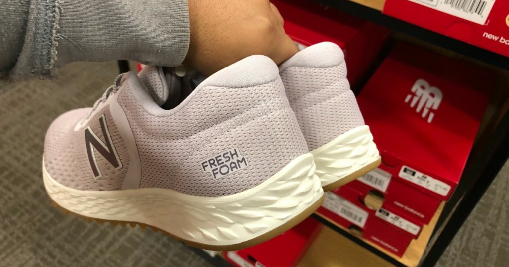 hand holding a pair of New Balance shoes
