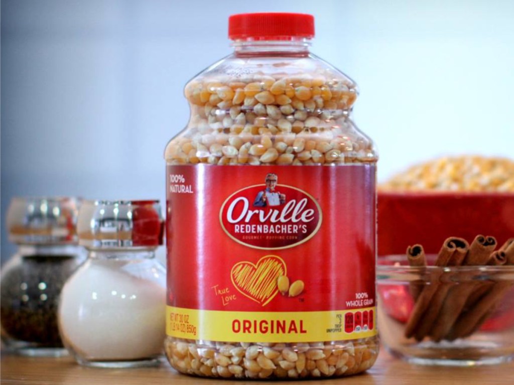 jar of popcorn kernels, bowl of popcorn, garlic, and spices on table