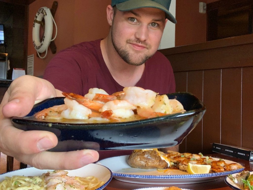 man holding plate of shrimp and showing the camera how a red lobster gift card is one of the popular graduation gift ideas