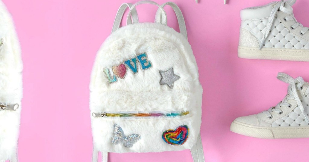 Faux white fur miniature backpack on pink background near matching shoes