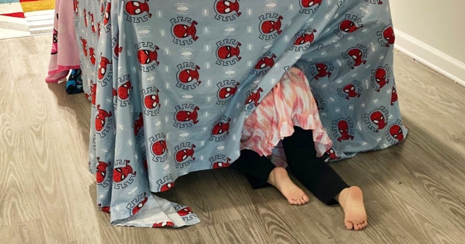 Little girl crawling into DIY table tent in dining room