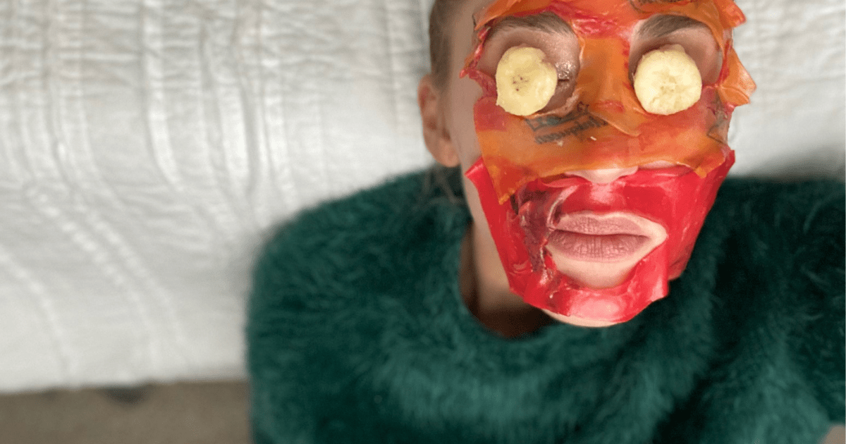 Woman laying down wearing Fruit Roll-Up mask with banana slices over eyes