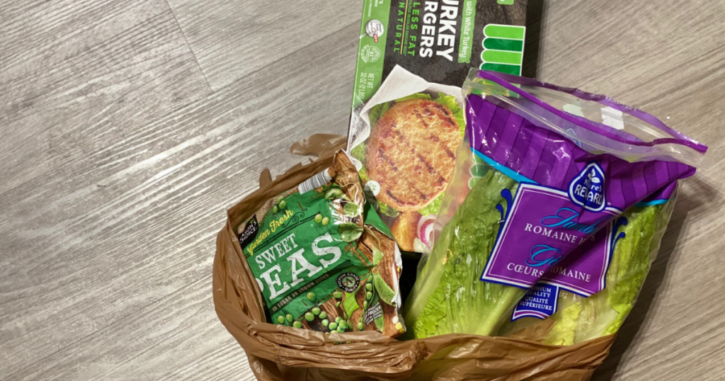 Lettuce, turkey burgers, and peas in a grocery bag in kitchen