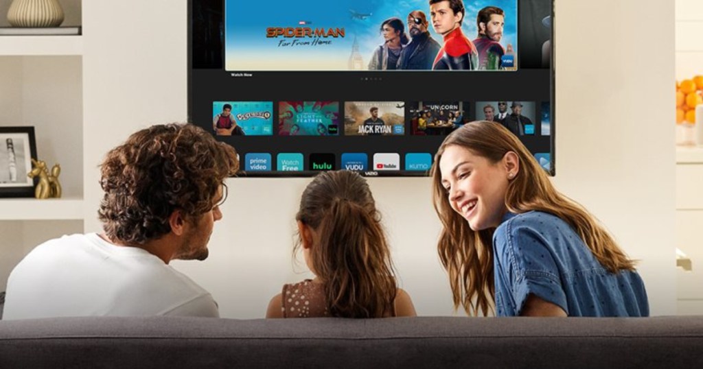 family sitting on couch in front of large tv