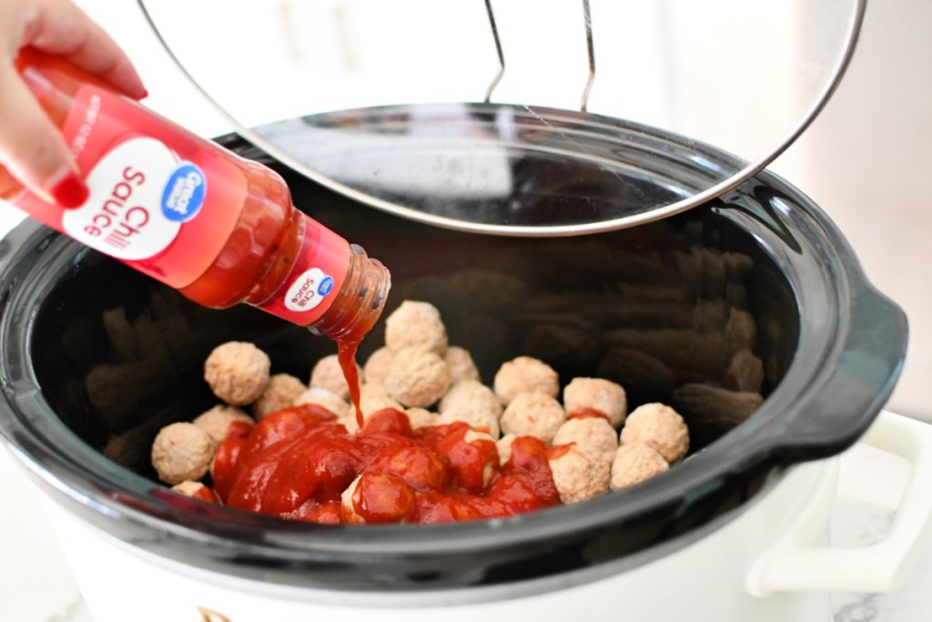 adding chili sauce to slow cooker meatballs