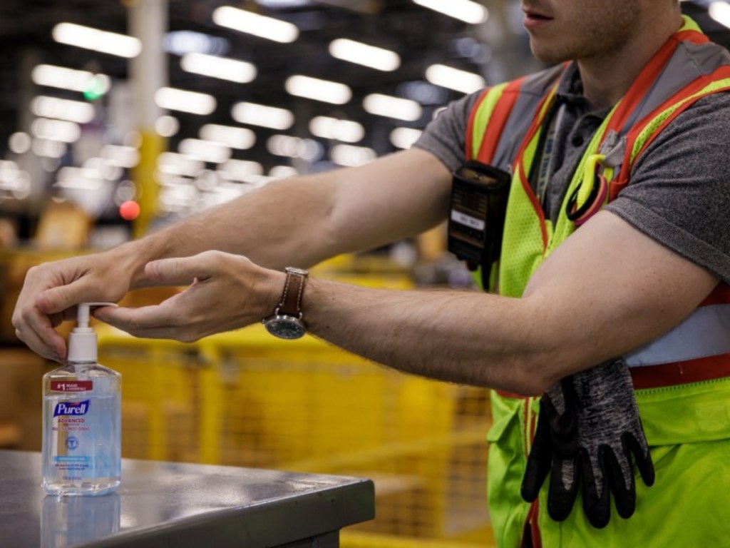 Amazon warehouse employee using hand sanitizer