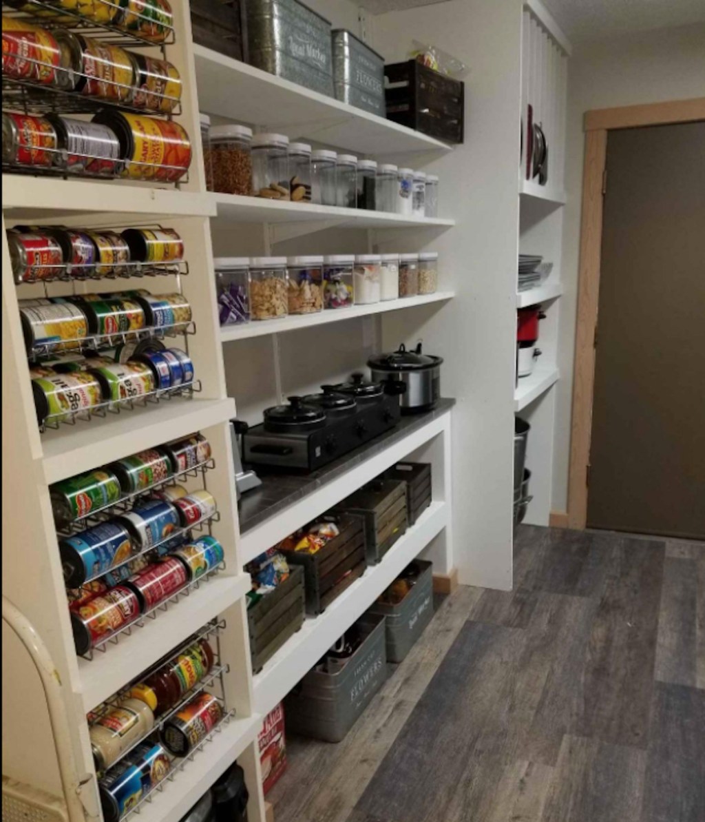 white pantry shelves with various cooking appliances and stacks of can on shelves