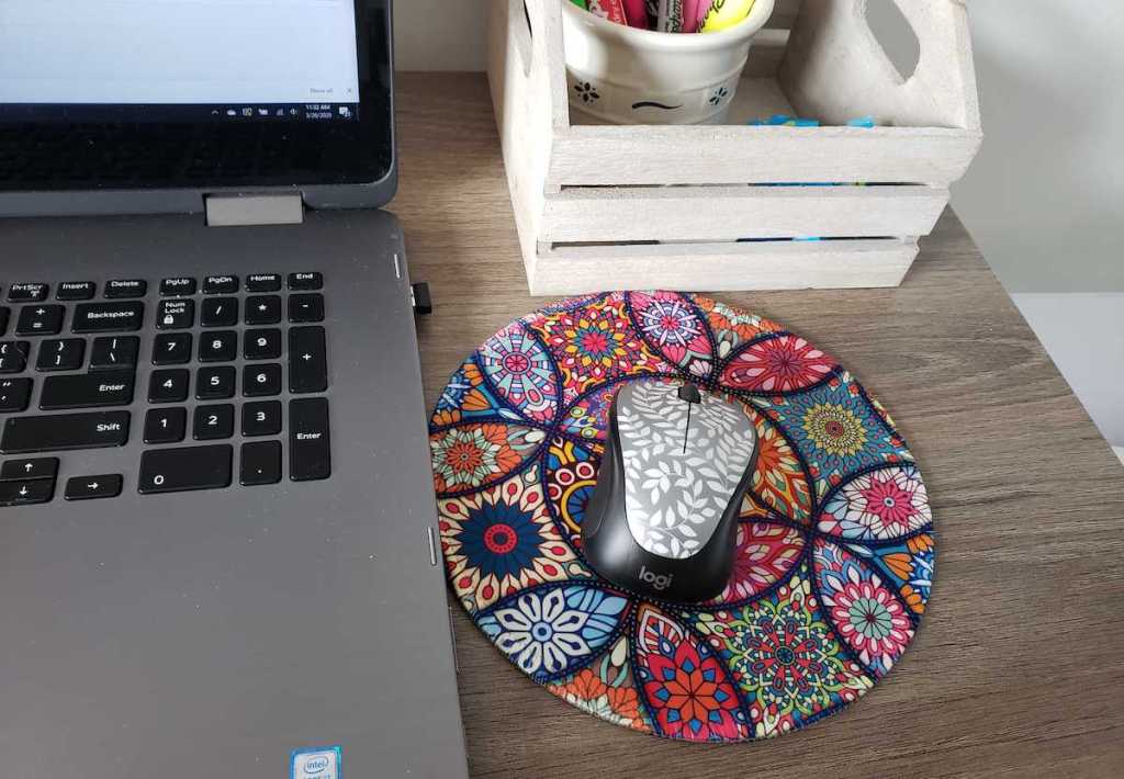 laptop next to colorful floral mouse and pad on desk