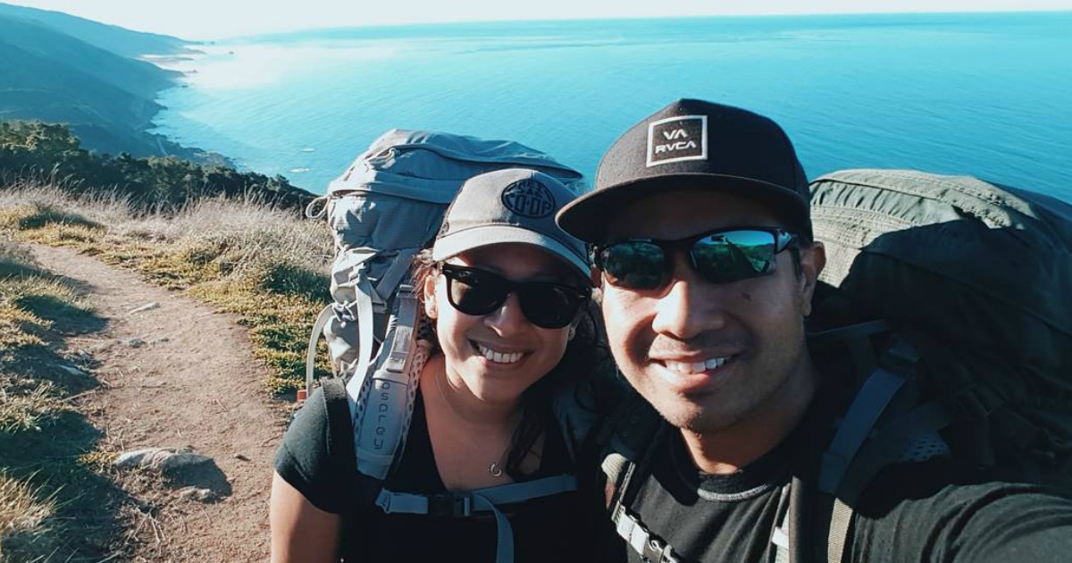 two people on trail by water taking scenic picture