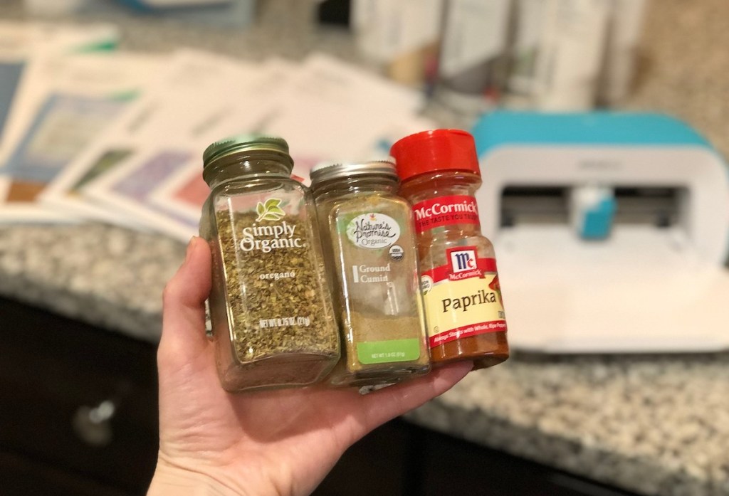 hand holding 3 types of spices with craft supplies in the background